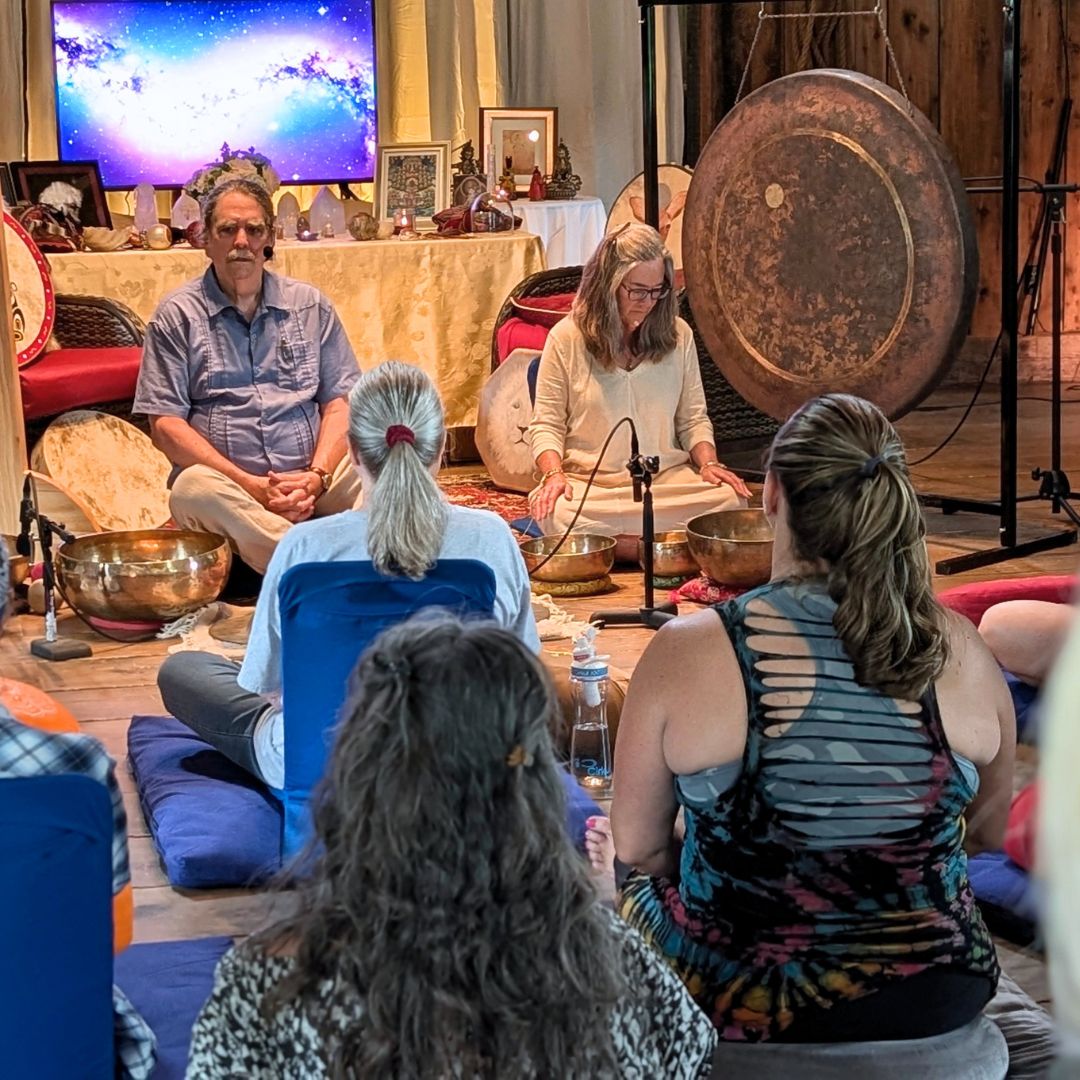 Group of people sitting in a circle with sound healing instruments in a room.