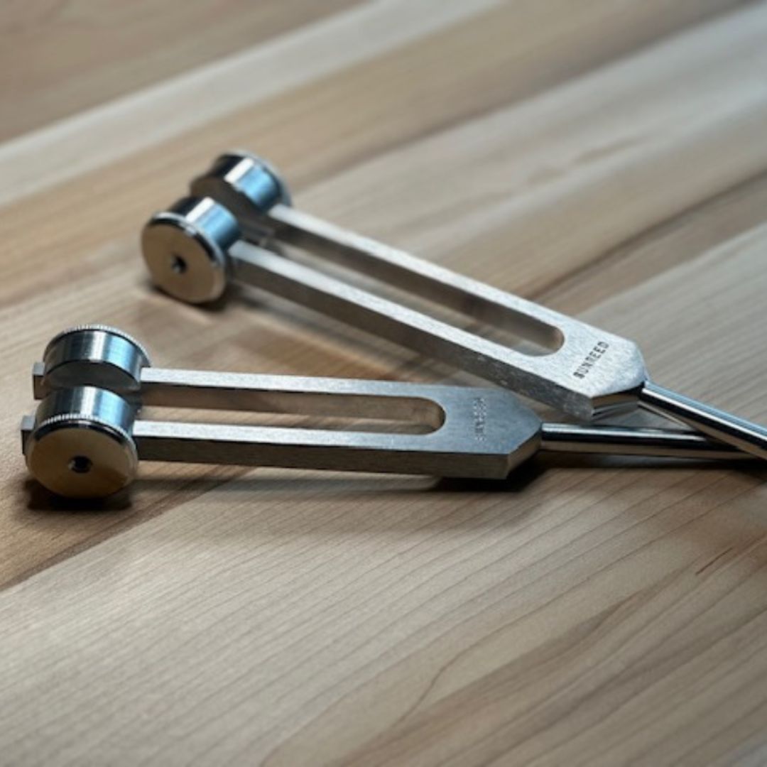 Two metal tuning forks with the label sunreed engraved on a wooden surface