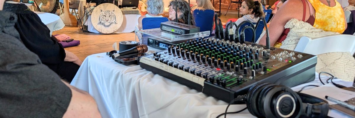 A mixing board set up on a table with people gathered around