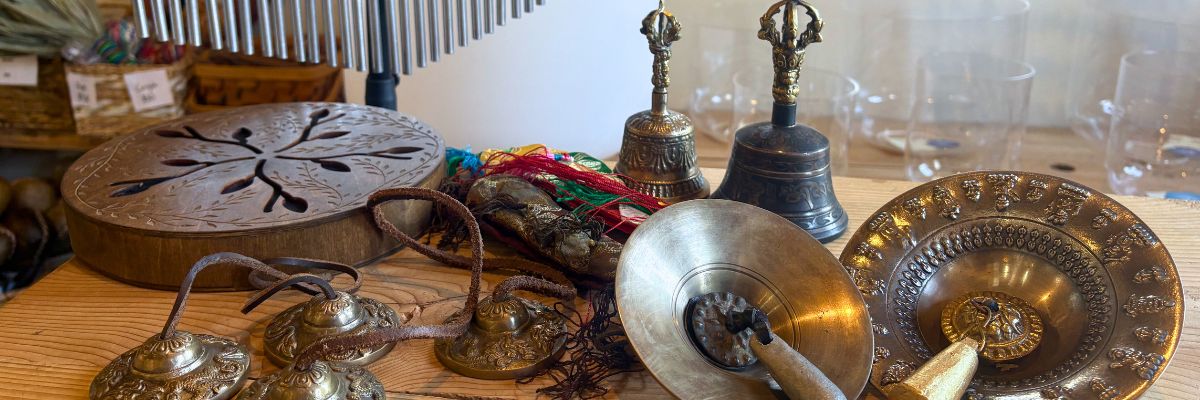 Antique looking tibetan bells and shangs on a wooden table with other sound instruments