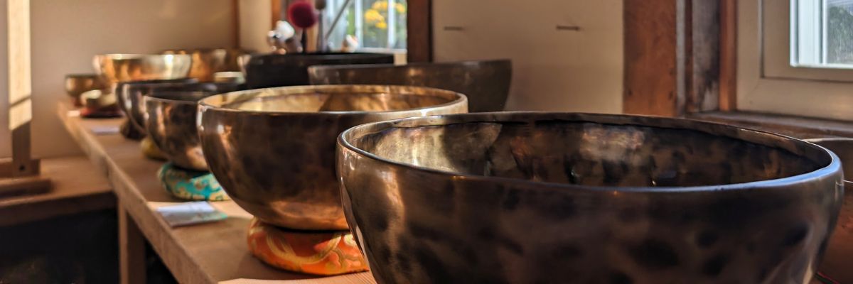 Several large Himalayan singing bowls arranged on a long wooden table