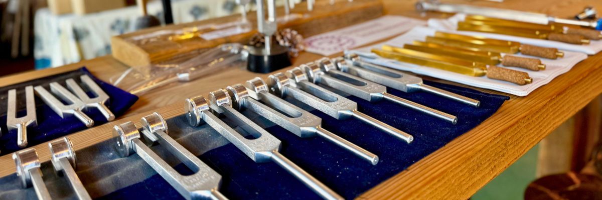 Multiple sets of tuning forks laid out on a wooden table