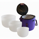 Set of white singing bowls with a purple carrying case on a white background.