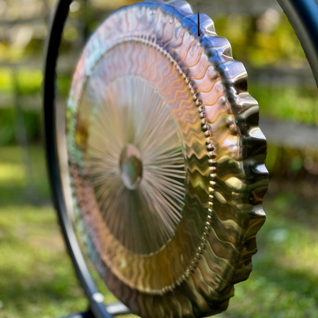 Decorative garden wheel with a metallic finish on a blurred natural background