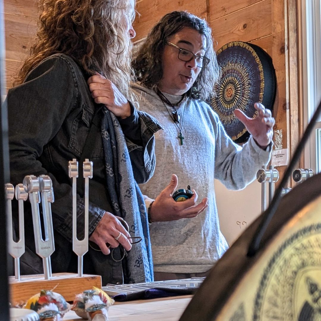 Two people interacting in a store with tuning forks, drums and rattles