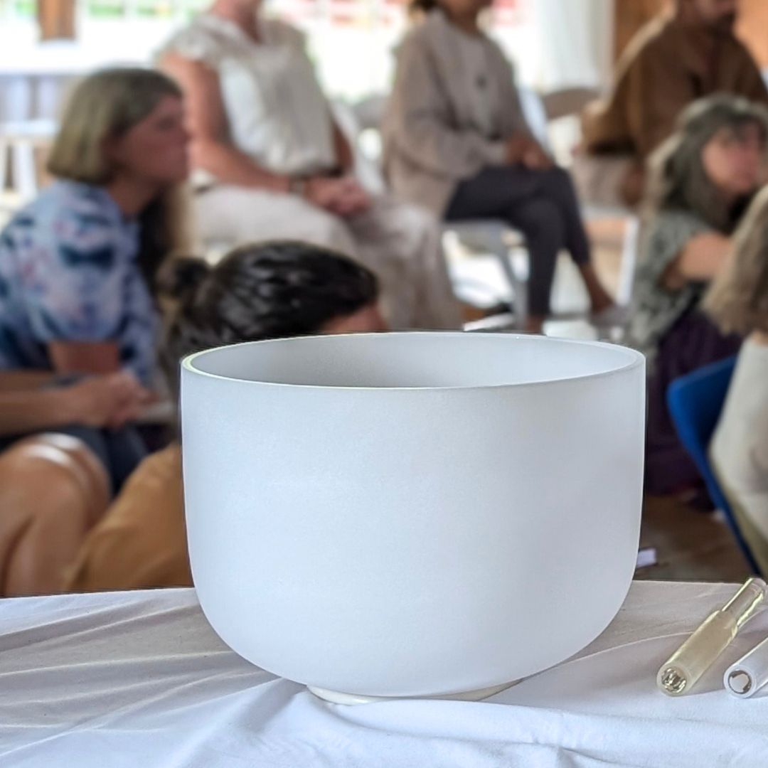 Crystal singing bowl on a table with people sitting in the background