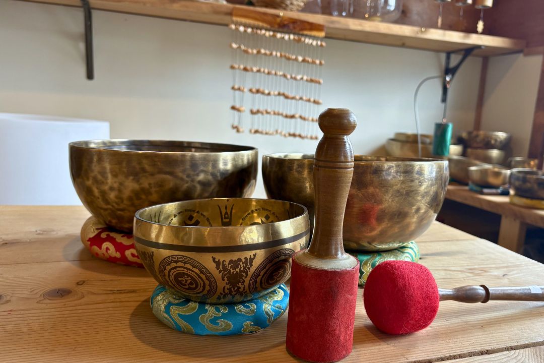 Set of metal singing bowls on a wooden surface with a mallet.