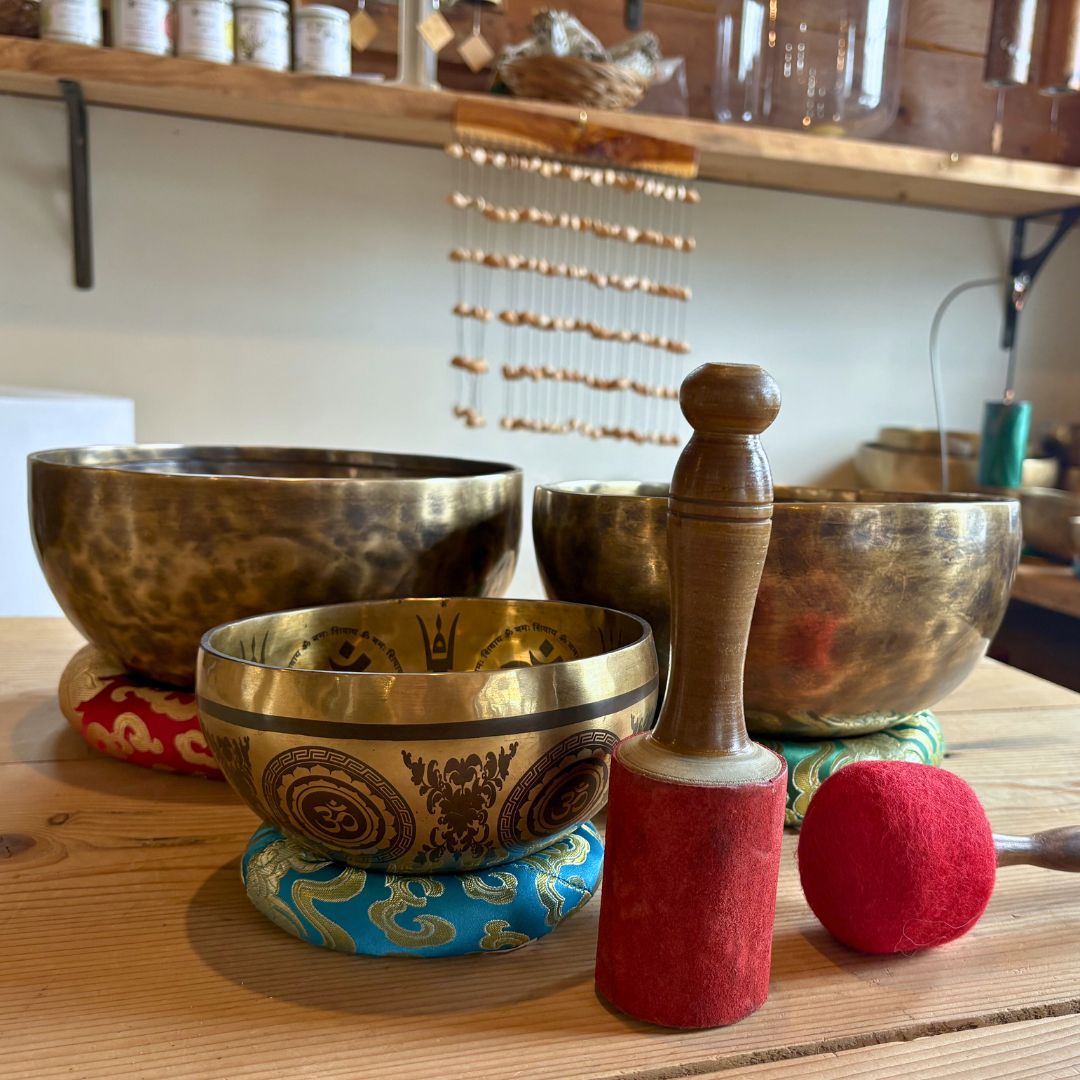Set of tibetan singing bowls on a wooden surface with a mallet.