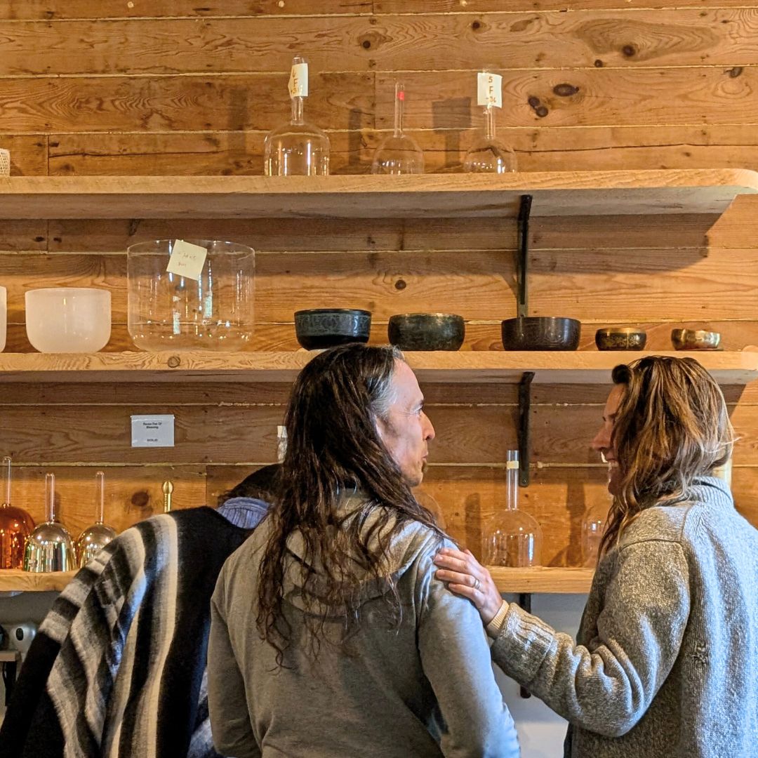 Two people standing in front of wooden shelves with various instruments